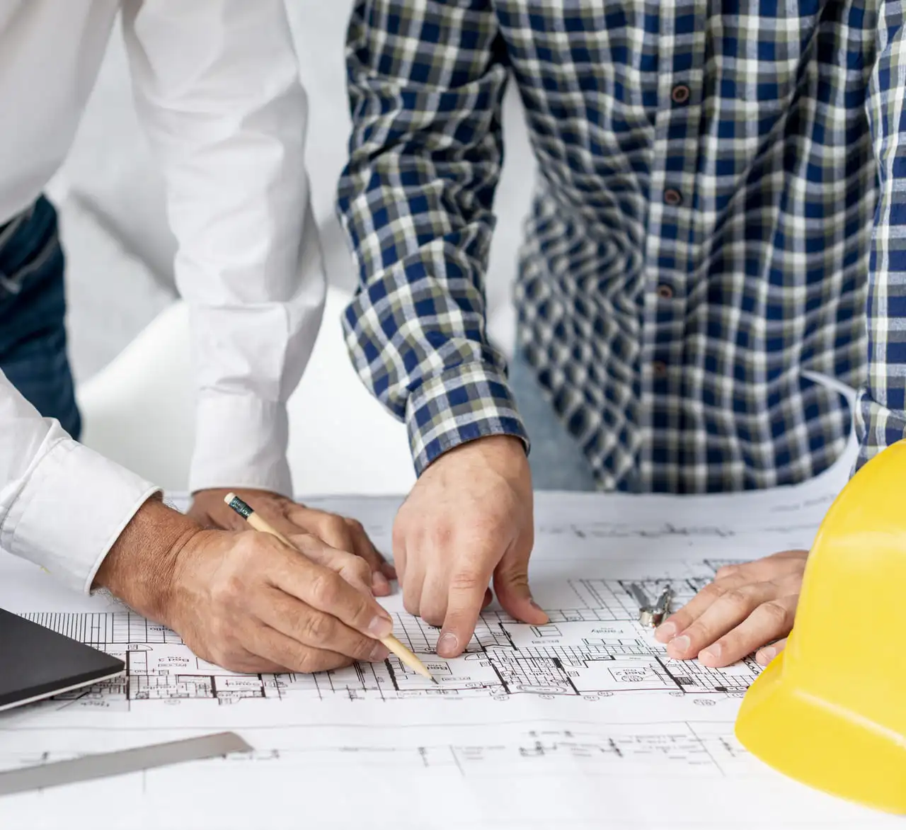 trabajadores revisando planos y mediciones sobre mesa de trabajo
