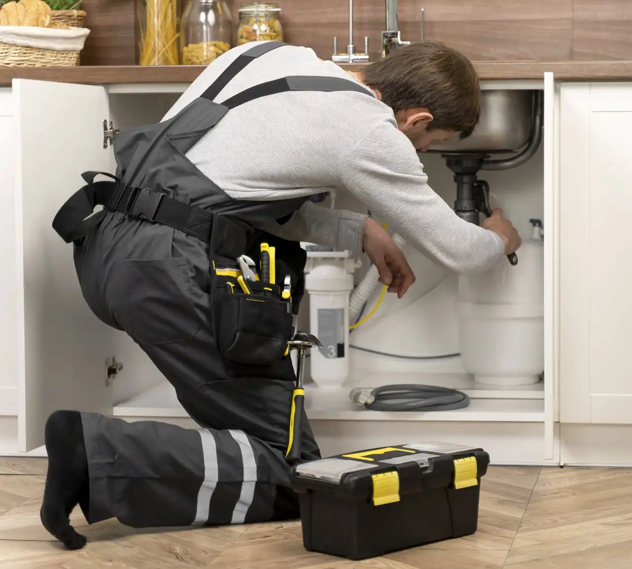 Técnico reparando fuga en fregadero durante una urgencia